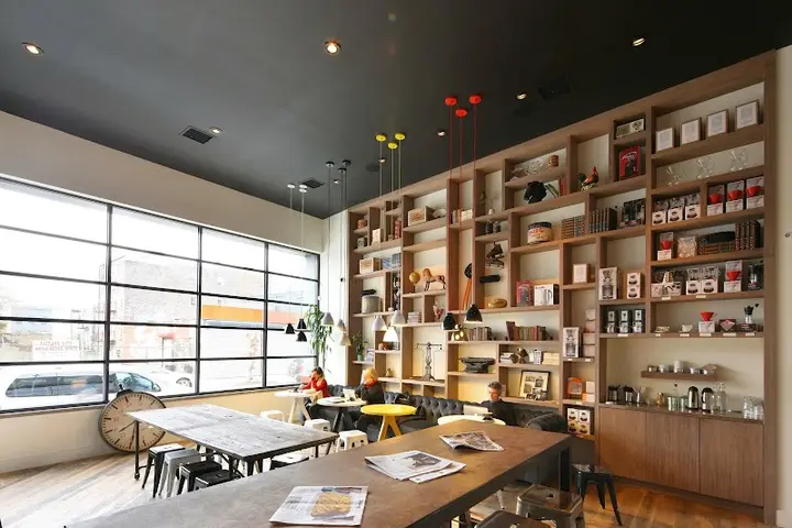 Partners Coffee on North 6th Street in Williamsburg: warehouse windows, a wood slat wall of retail coffee, and communal tables