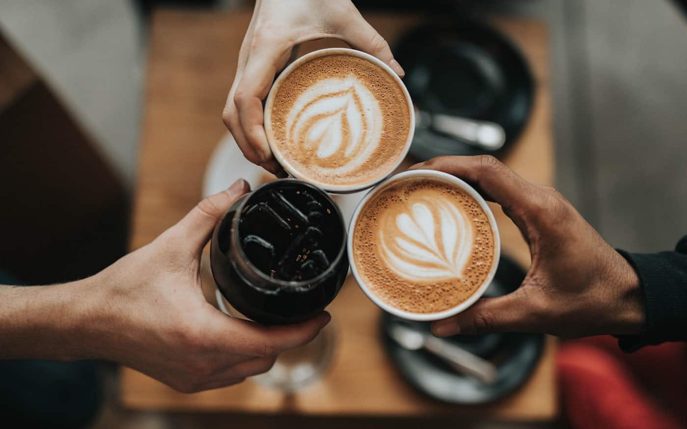 Whole coffee beans beside a brewer and grinder on a kitchen counter